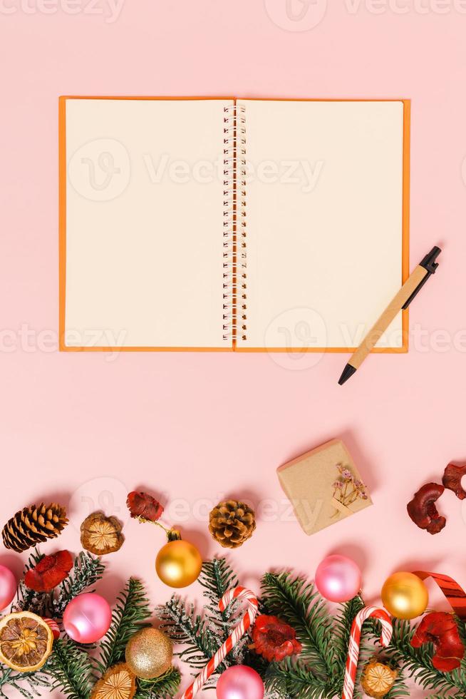 minimal kreativ lägenhet av vinterjulens traditionella komposition och nyårshelger. ovanifrån öppen mockup svart anteckningsbok för text på rosa bakgrund. håna och kopiera rymdfotografering. foto