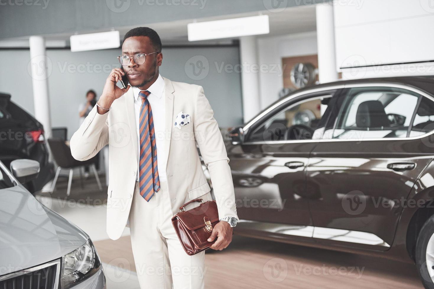 ung svart affärsman på bilsalong bakgrund. bil försäljning och hyra koncept foto