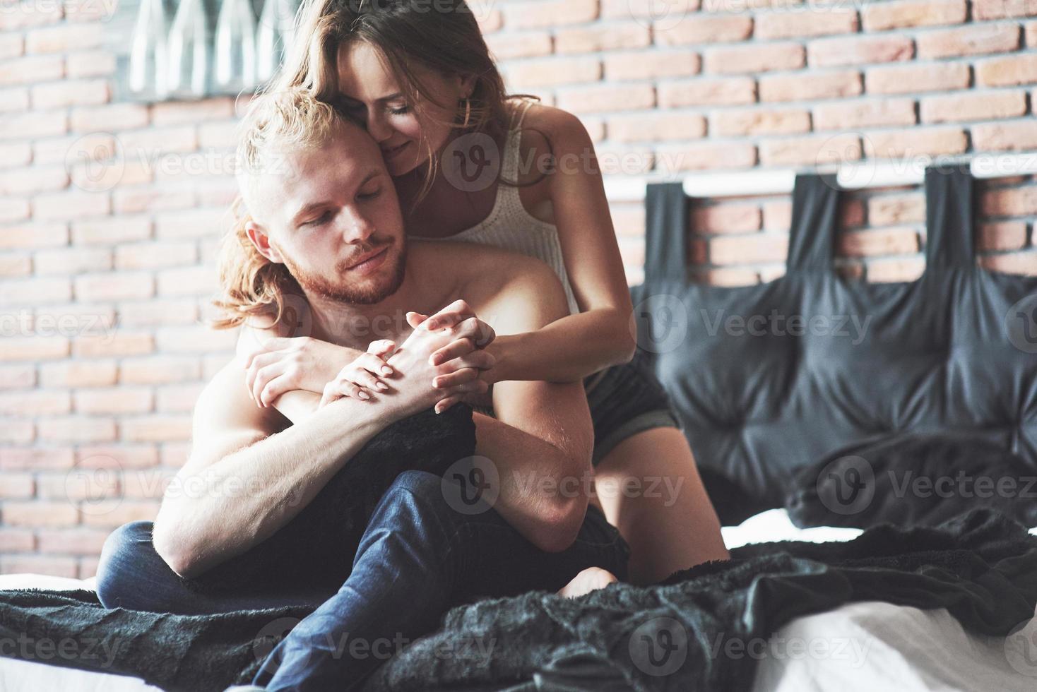 attraktiva unga älskare har par som leker tillsammans i sängen och bär sexiga underkläder på ett hotellrum. foto