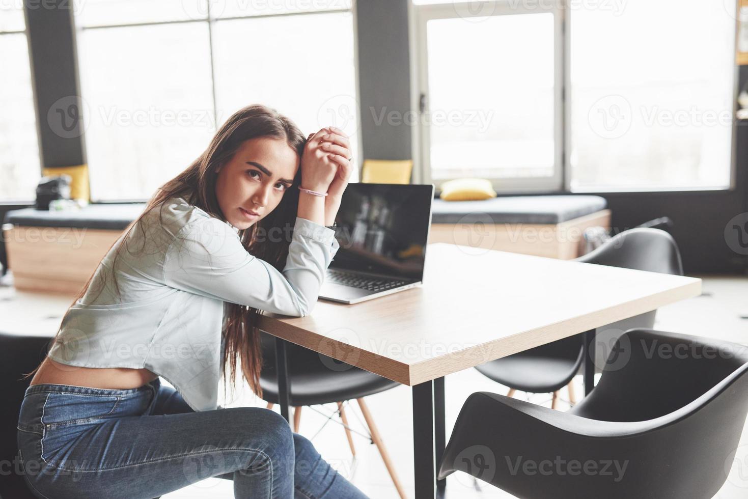 kvinnlig student som använder bärbar dator medan du sitter på café. koncentrerad ung kvinna frilansare på jobbet foto