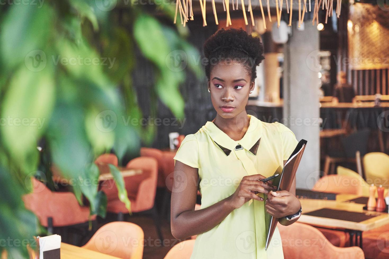 ung afroamerikansk tjej med mörkt lockigt hår fundersamt på ett café. foto