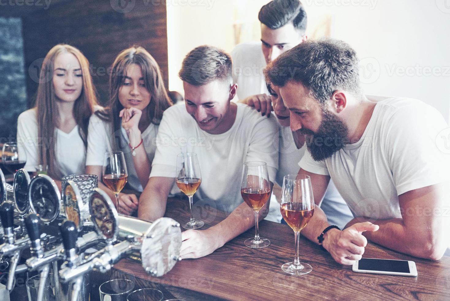 fritid och kommunikation koncept. grupp glada leende vänner som njuter av drinkar och pratar i baren eller puben foto