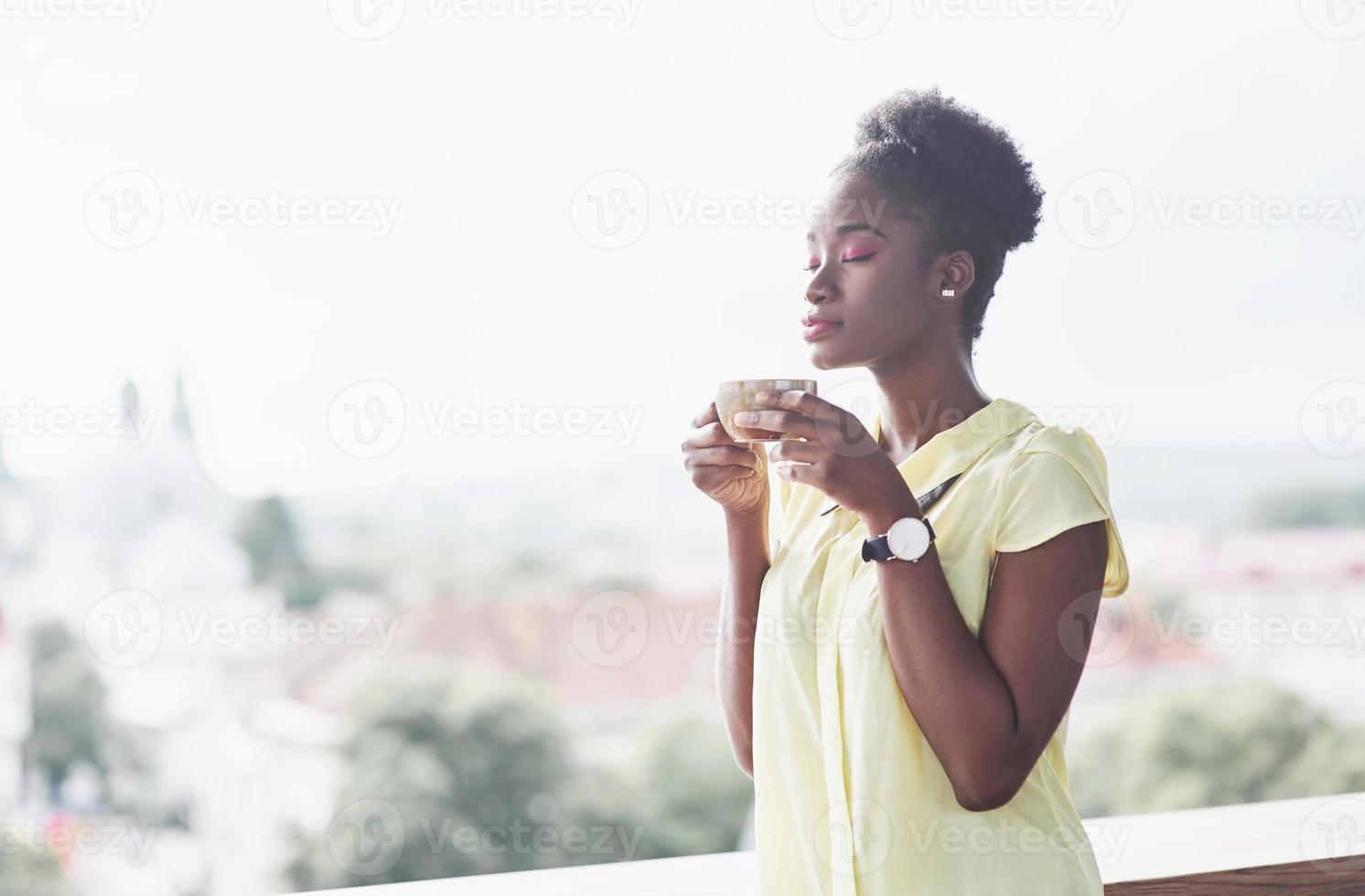 ung afroamerikansk tjej med mörkt lockigt hår fundersamt på ett café. vackert mysigt ställe. foto