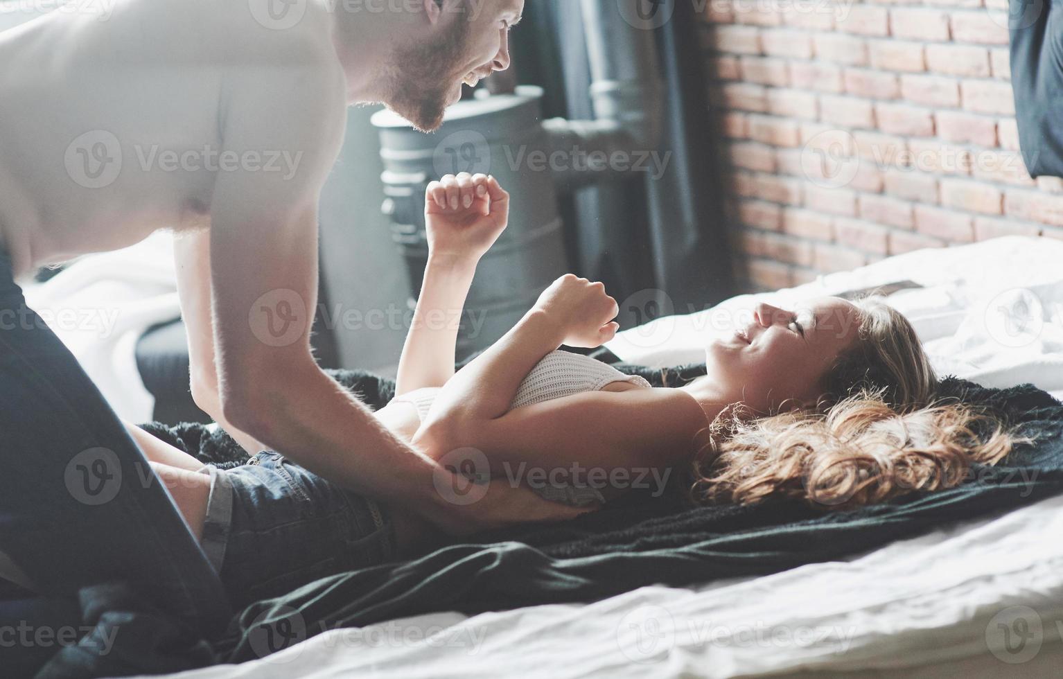 attraktiva unga älskare har par som leker tillsammans i sängen och bär sexiga underkläder på ett hotellrum. foto
