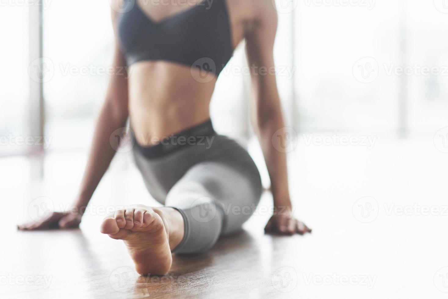 en vacker yogakvinna övar i ett rymligt ljust gym med stora fönster. foto