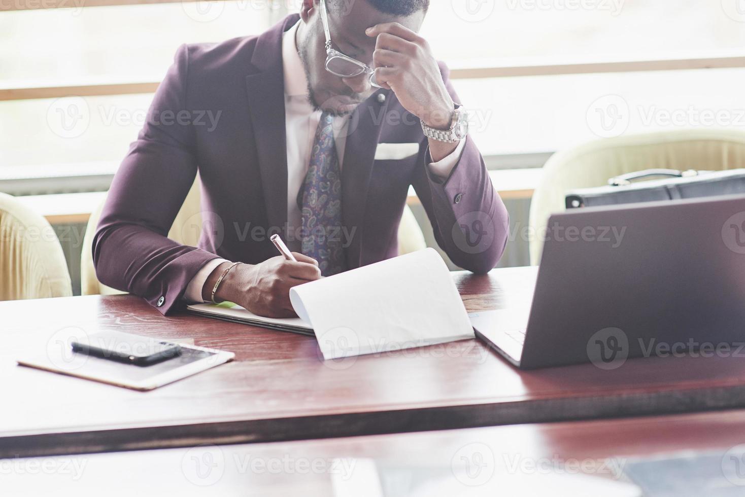 en vacker snygg afroamerikansk affärskvinna som bär kostym använder sin bärbara dator medan han arbetar. foto