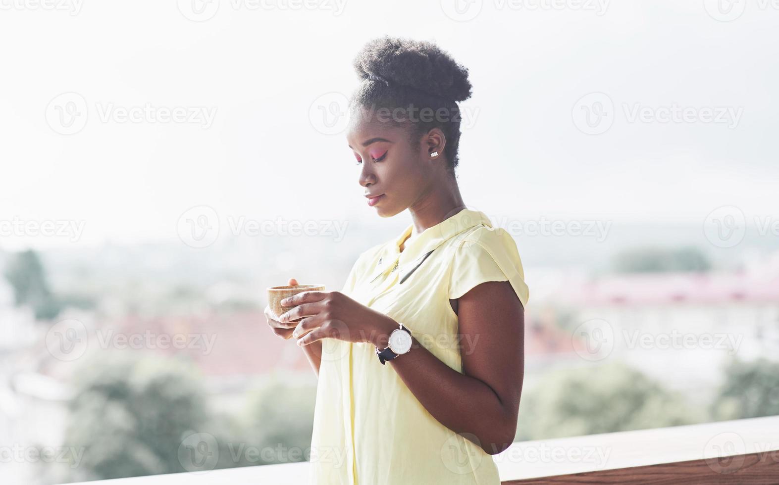 ung afroamerikansk tjej med mörkt lockigt hår fundersamt på ett café. vackert mysigt ställe. foto