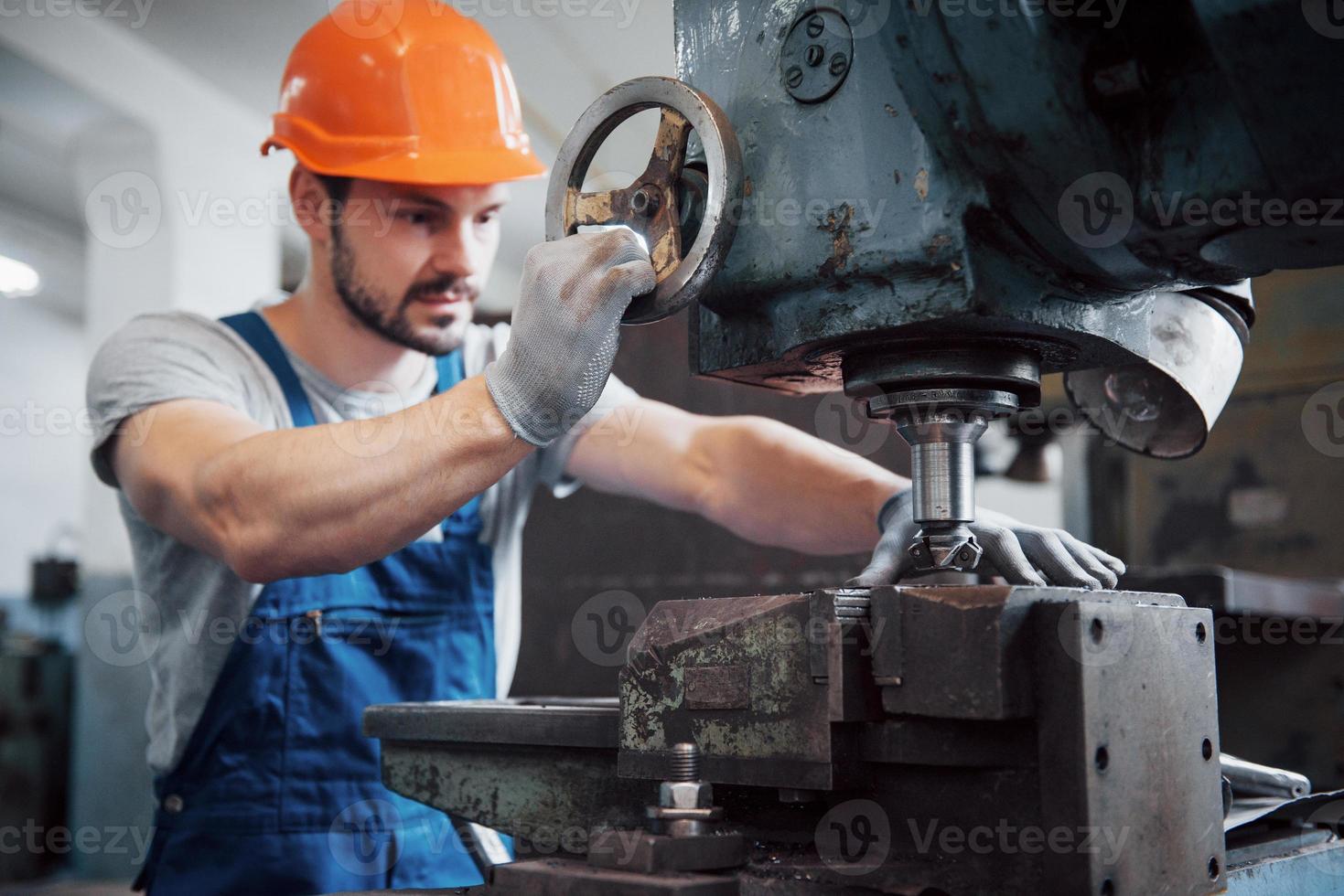 porträtt av en ung arbetare i en hård hatt på en stor metallbearbetningsanläggning. ingenjören servar maskinerna och tillverkar delar till gasutrustning foto