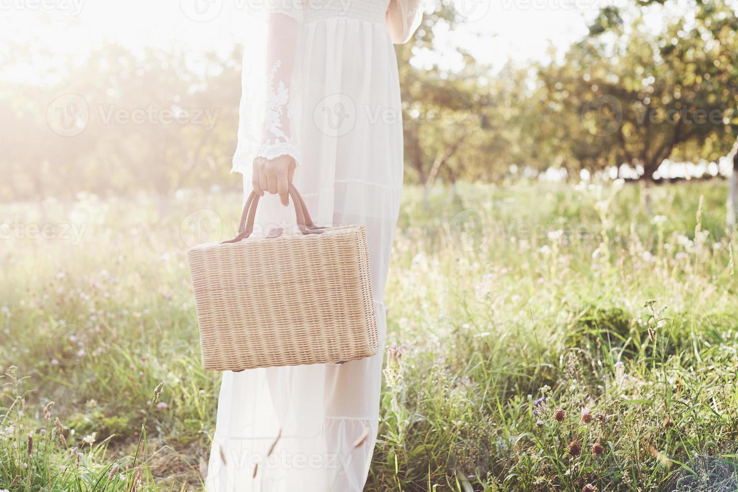 vacker ung kvinna klädd i elegant vit klänning och njuter av vacker solig eftermiddag i en sommar trädgård foto