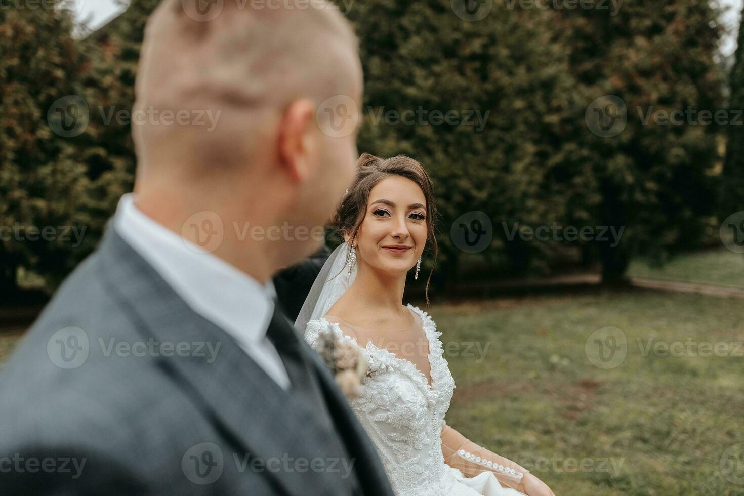 eleganta brud och brudgum ömt omfamning och kyss. skön brud med modern bukett fattande eleganta brudgum i höst parkera. sensuell romantisk ögonblick. bröllop. eleganta och skön. foto