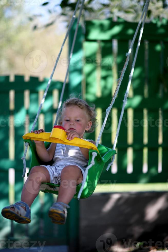 vacker baby pojke med barn swing poserar fotograf foto