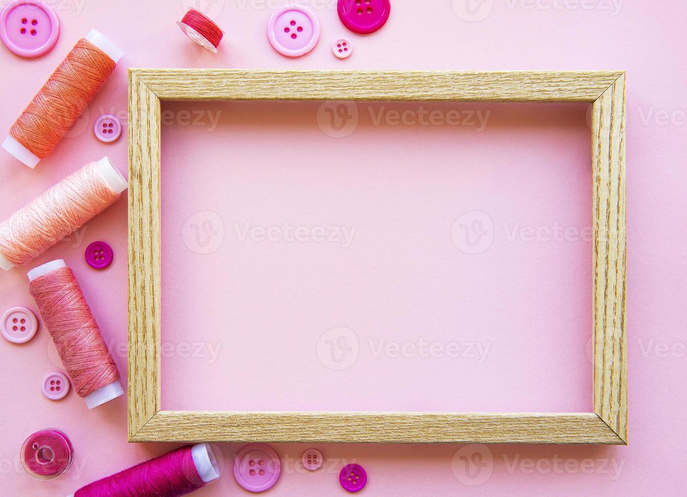 trådrullar och knappar i rosa toner på en rosa bakgrund foto