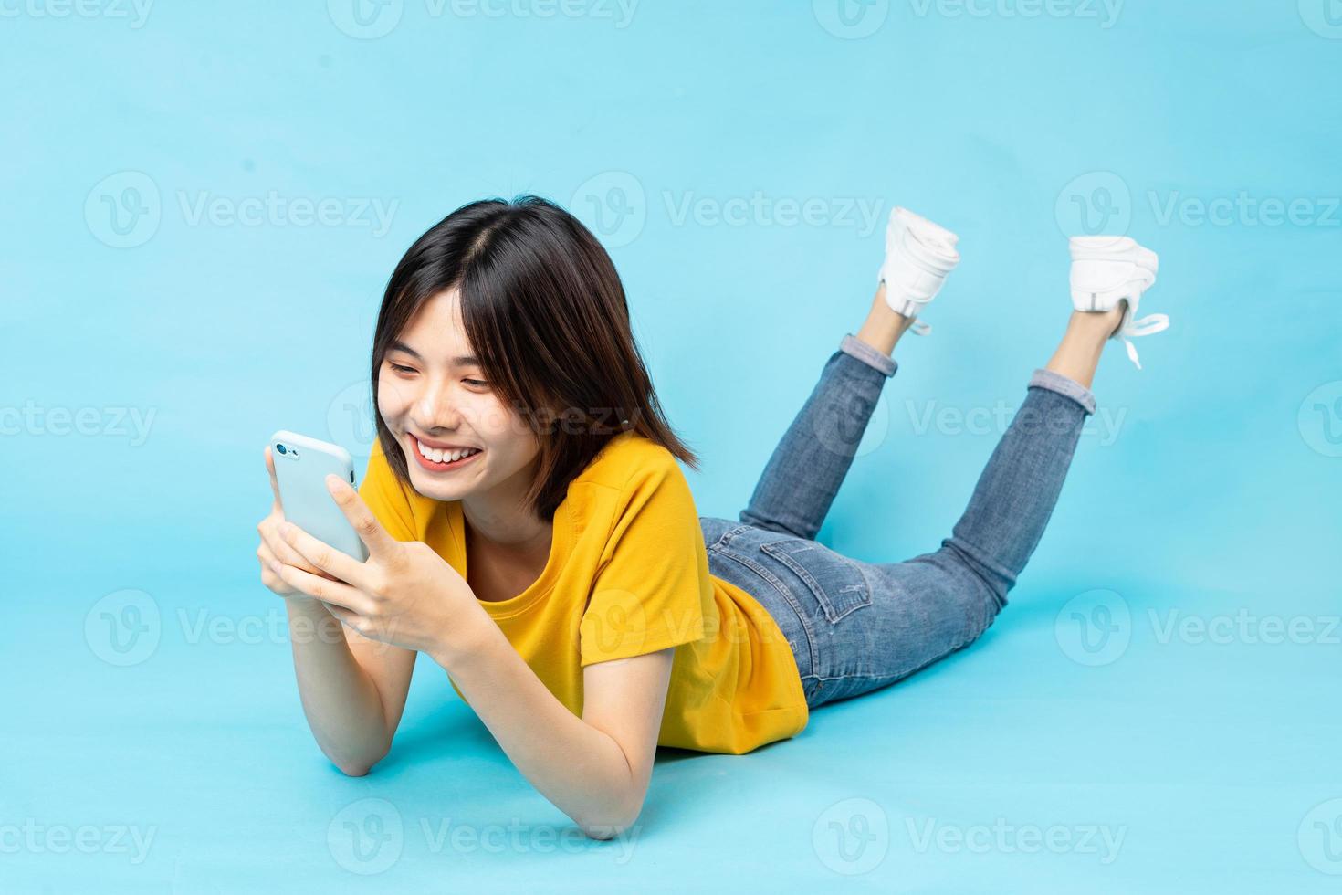 helkroppsporträtt av den lekfulla asiatiska flickan som ligger på blå bakgrund foto