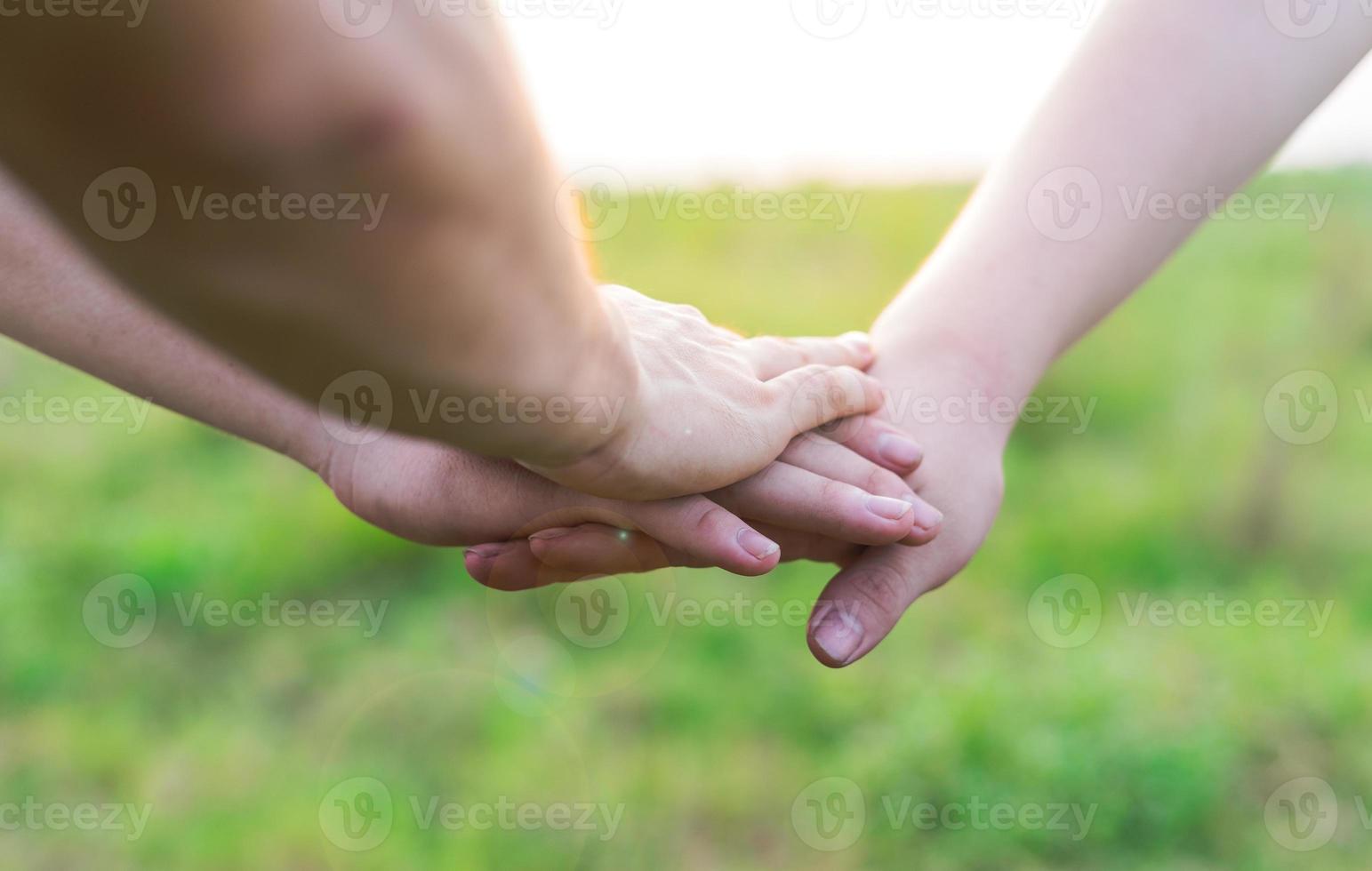 närbild av unga människor som sätter ihop händerna. vänner som håller varandra visar solidaritet och lagarbete. foto