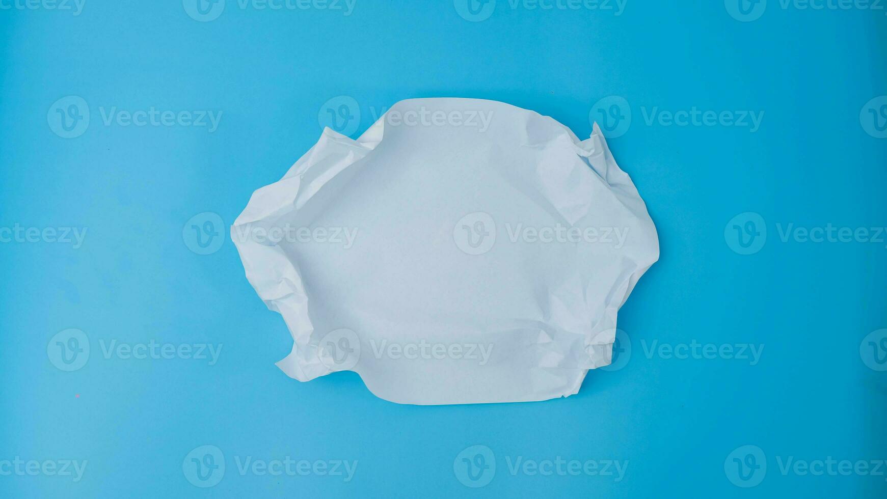 en papper boll är spridning ut in i en tom ark på blå bakgrund. skrynkliga tom vit papper med kopia Plats för text eller reklam Plats. foto