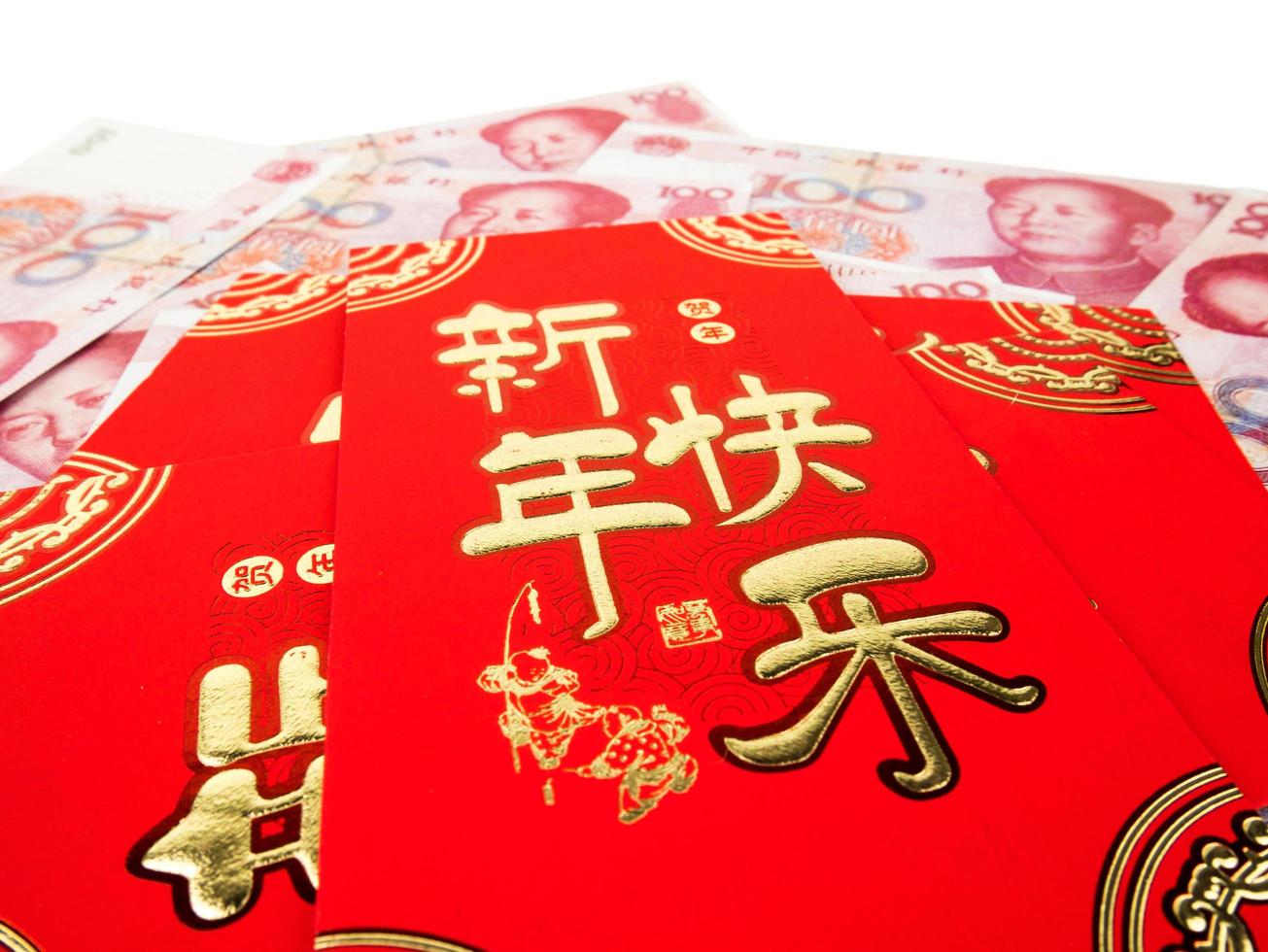kinesiska röda kuvert över kinesiska pengar hundra yuan sedlar hög hög isolerad på vit bakgrund. kinesisk text på kuvert som betyder gott kinesiskt nytt år foto
