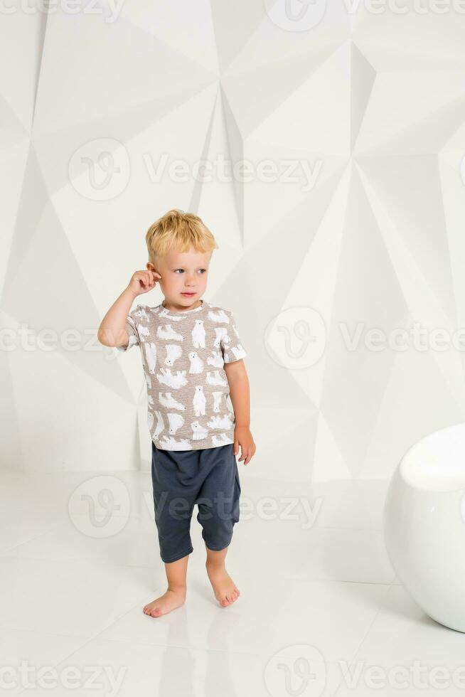 liten pojke i en t-shirt och shorts på en vit bakgrund foto