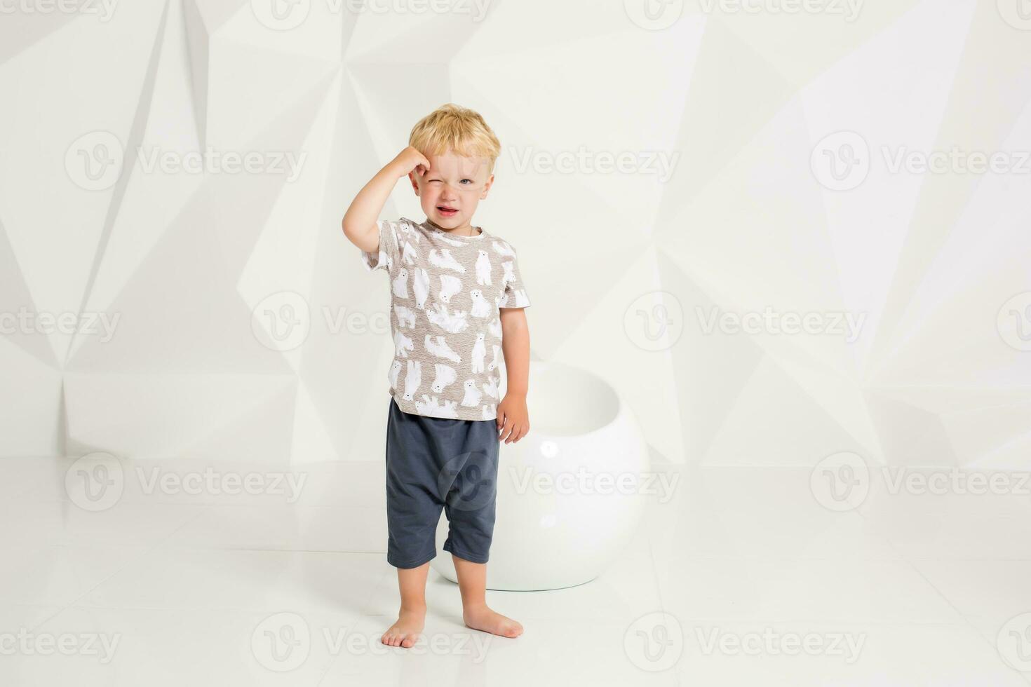 liten pojke i en t-shirt och shorts på en vit bakgrund foto