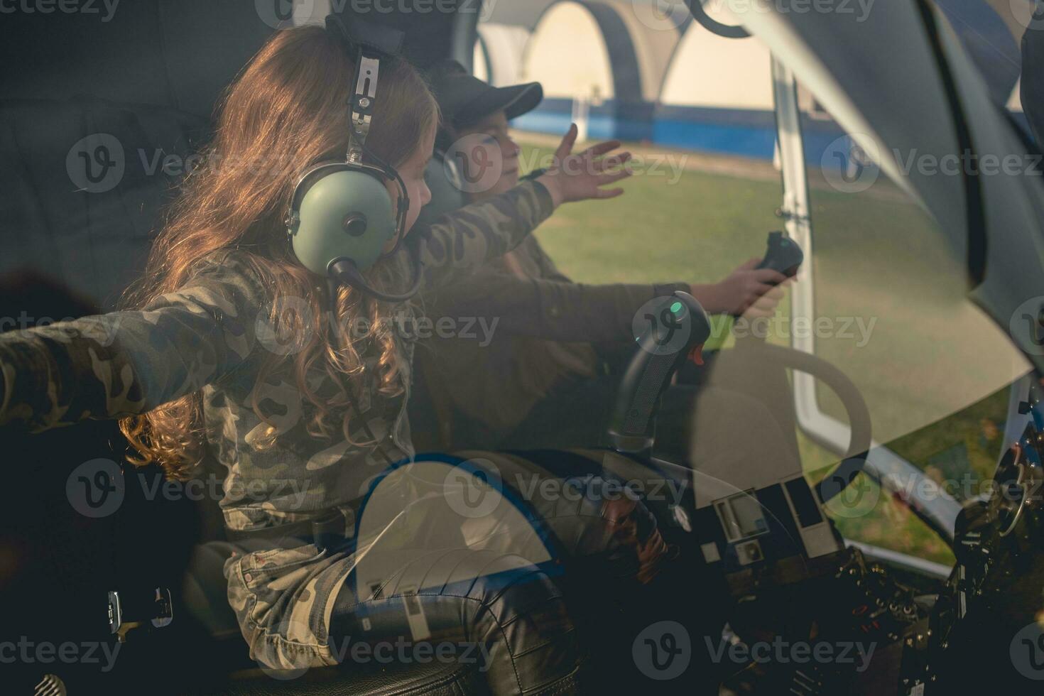 preteen flicka med vapen utsträckt till sida Sammanträde i helikopter cockpit foto