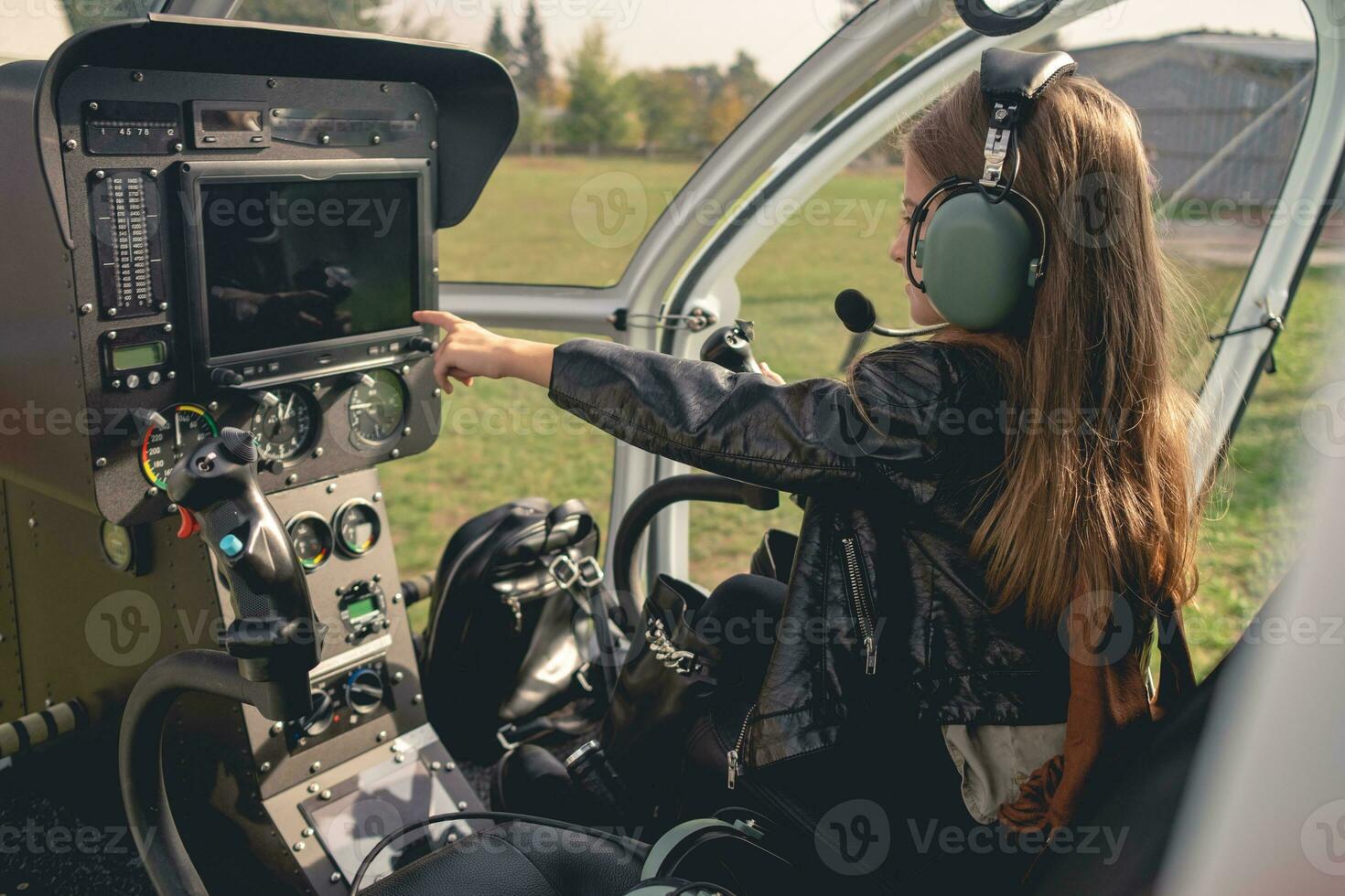 preteen flicka i headsetet pekande på instrumentbräda i helikopter cockpit foto