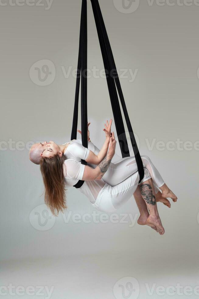 skön flicka och ett atletisk man i en vit sport kostymer är utför ett akrobatisk element i en studio. foto