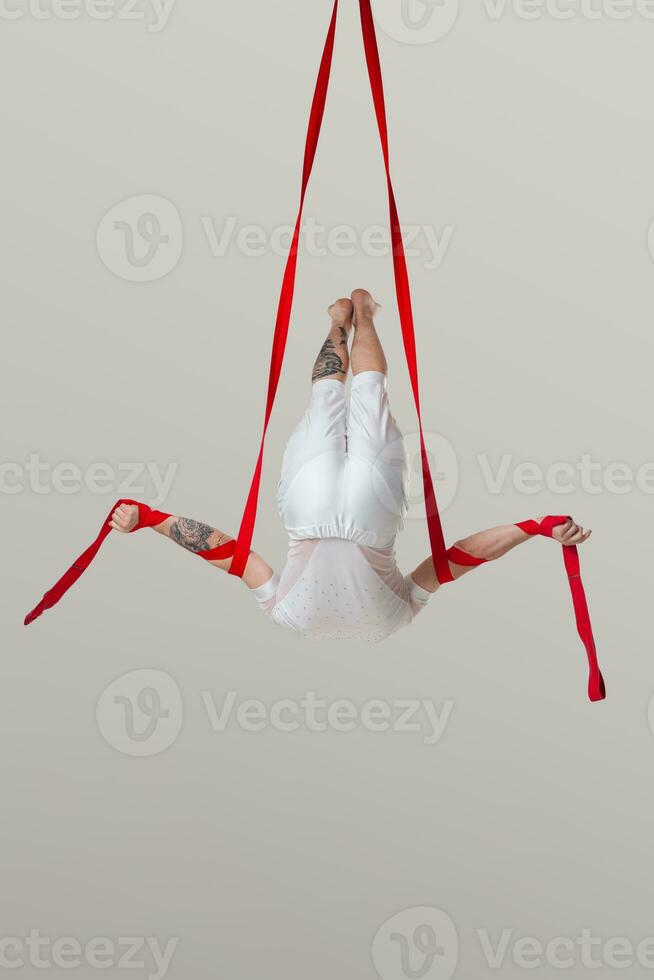 atletisk man i en vit sport kostym är utför ett akrobatisk element i en studio. foto