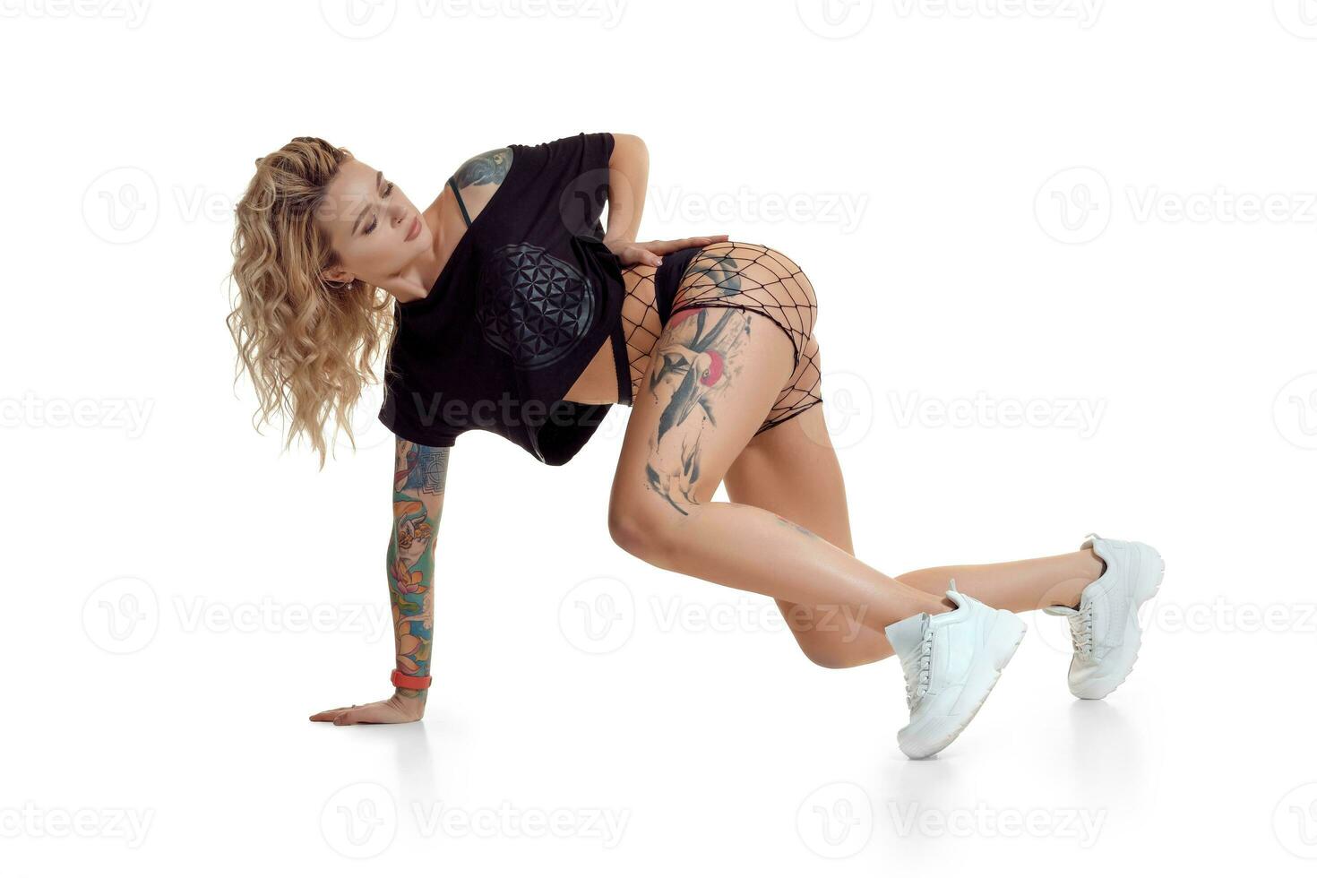 skön blond flicka i byte shorts och fisknät dans twerk isolerat på vit bakgrund foto