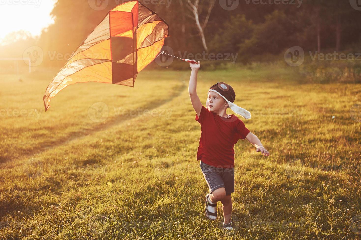 lyckligt barn lanserar en drake i fältet vid solnedgången. liten pojke och flicka på sommarlovet foto