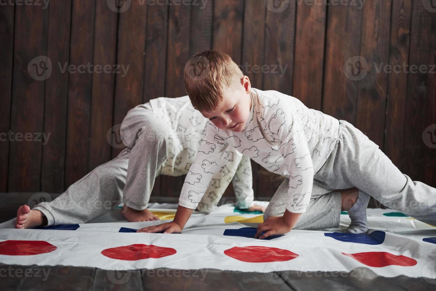 två av glada barn som leker på twister i huset. bror och syster har roligt på semestern foto