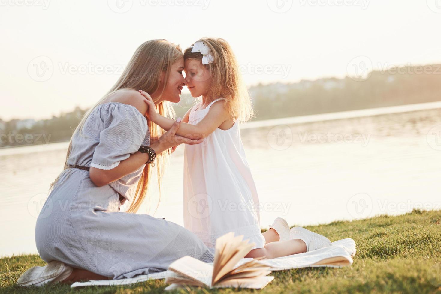 glad ung mamma med en lekfull dotter i en park nära vattnet foto