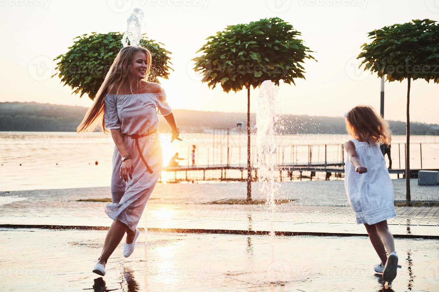 mamma med bebis nära fontänen i solnedgången foto