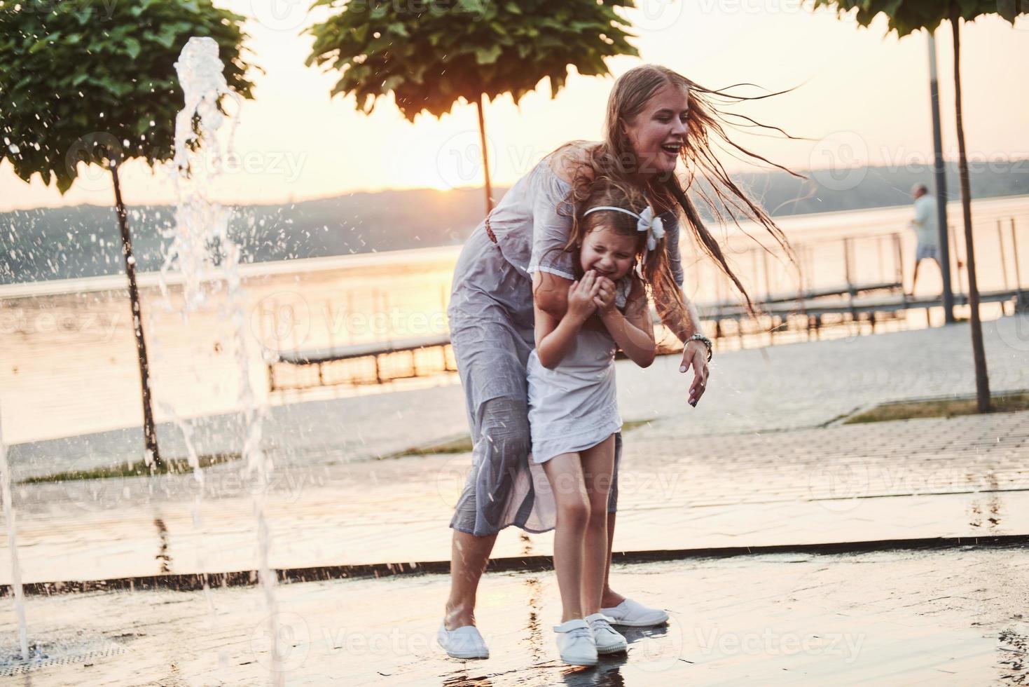 mamma med bebis nära fontänen i solnedgången foto