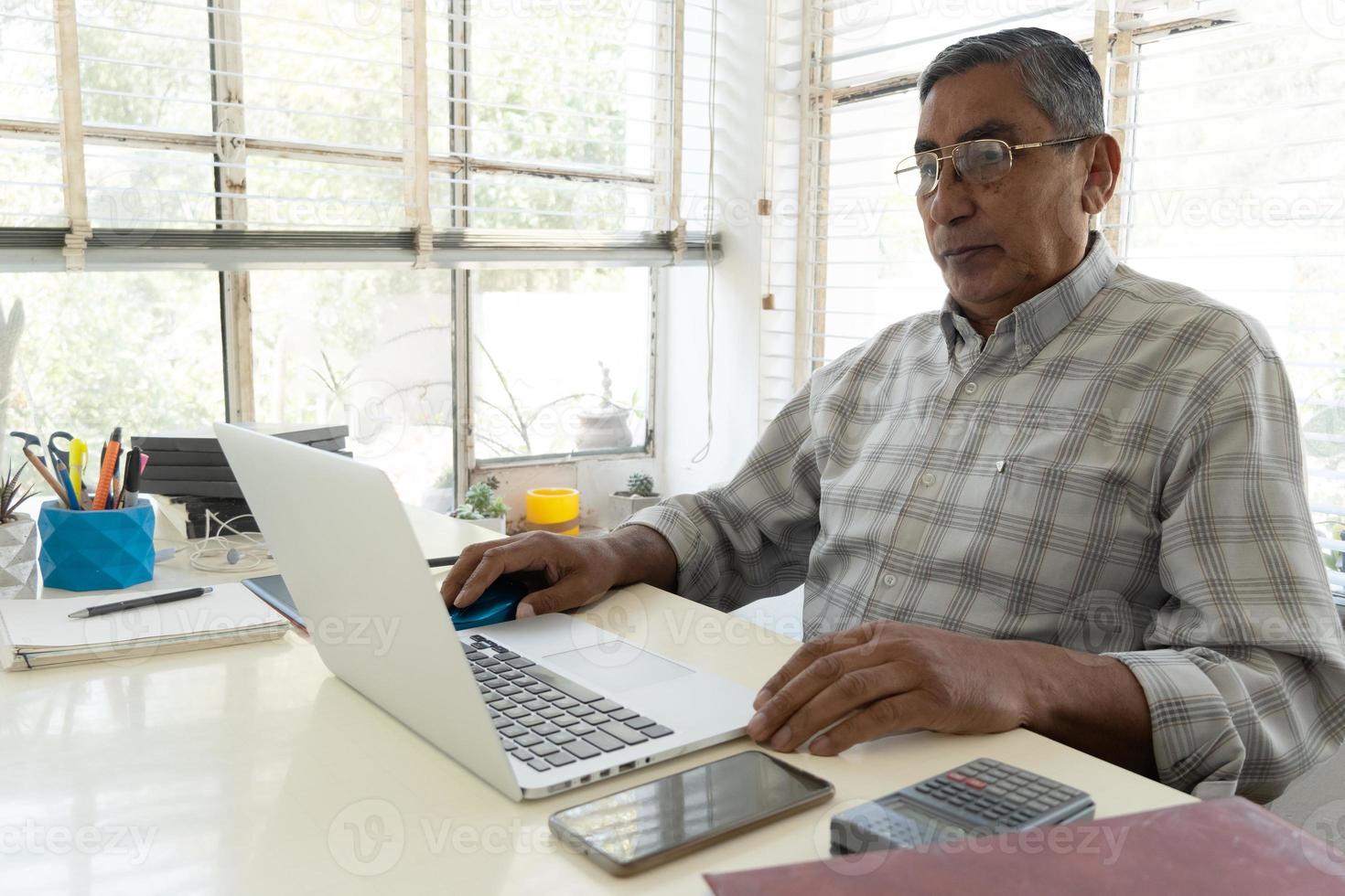 porträtt av självsäker affärsman med bärbar dator vid skrivbordet på kontoret foto