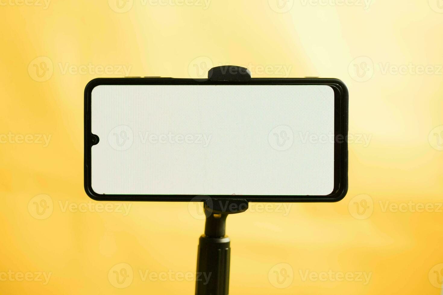 landskap telefon med vit skärm fast till stativ på gul bakgrund, för attrapp design. foto