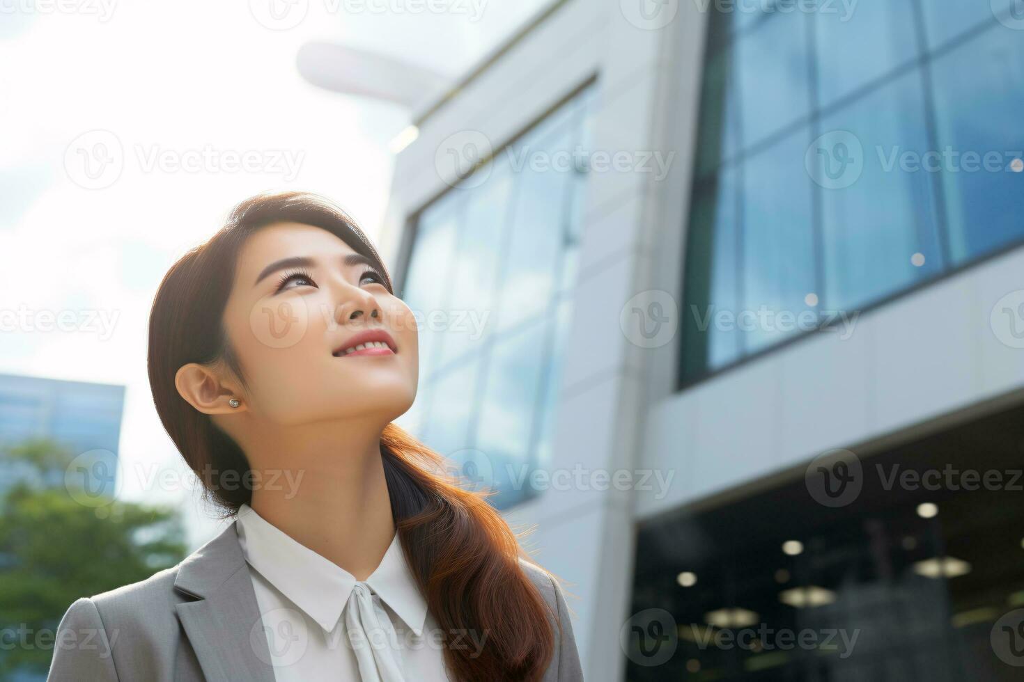 ai genererad Lycklig ung asiatisk företag kvinna stående på gata utanför modern kontor byggnad i de stad. porträtt av professionell affärskvinna. kontor arbetstagare ser upp till de himmel och leende. foto