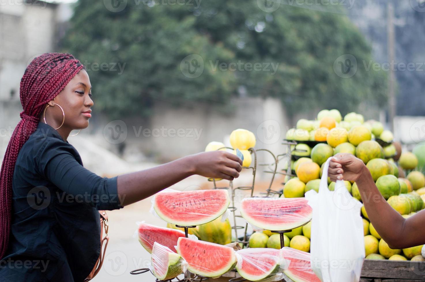 ung kvinna köper frukt på gatumarknaden. foto
