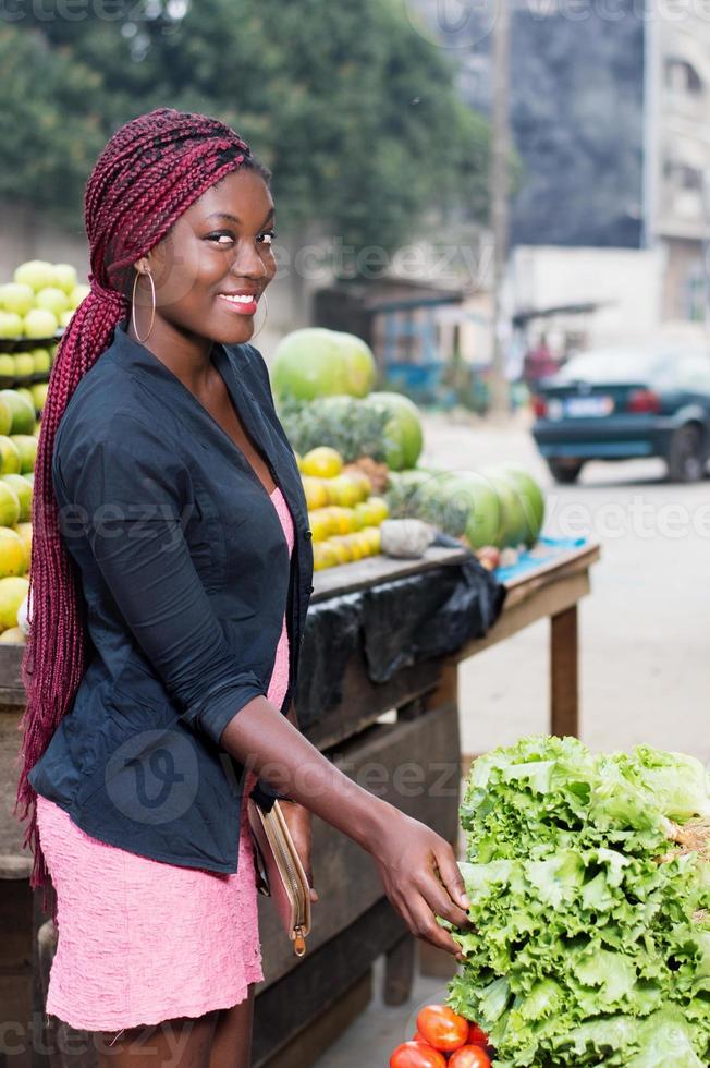 leende ung kvinna framför grönsaker foto