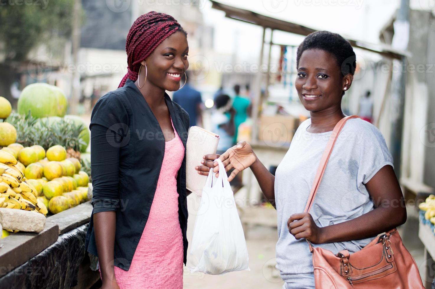 porträtt av unga leende kvinnor som står på fruktmarknaden. foto