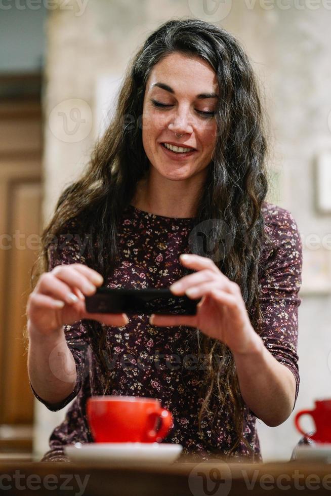 ung kvinna med lite grått hår med smartphone i ett café. foto