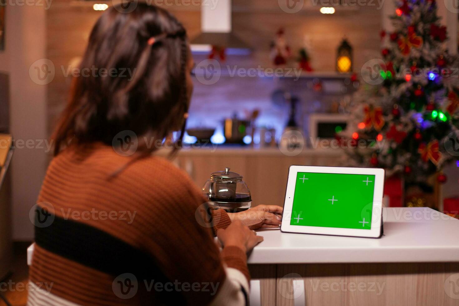caucasian vuxen tittar på grön skärm teknologi på läsplatta Sammanträde på kök disken. ung kvinna använder sig av digital krom nyckel begrepp för bakgrund mall, attrapp grej app på visa foto