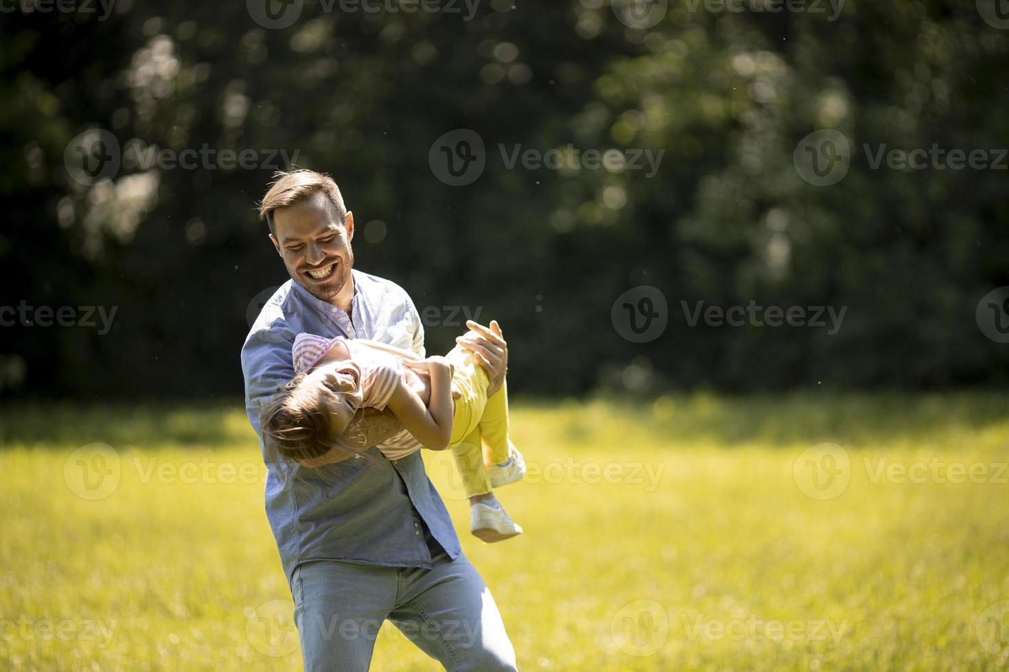 far med dotter som har kul på gräset i parken foto