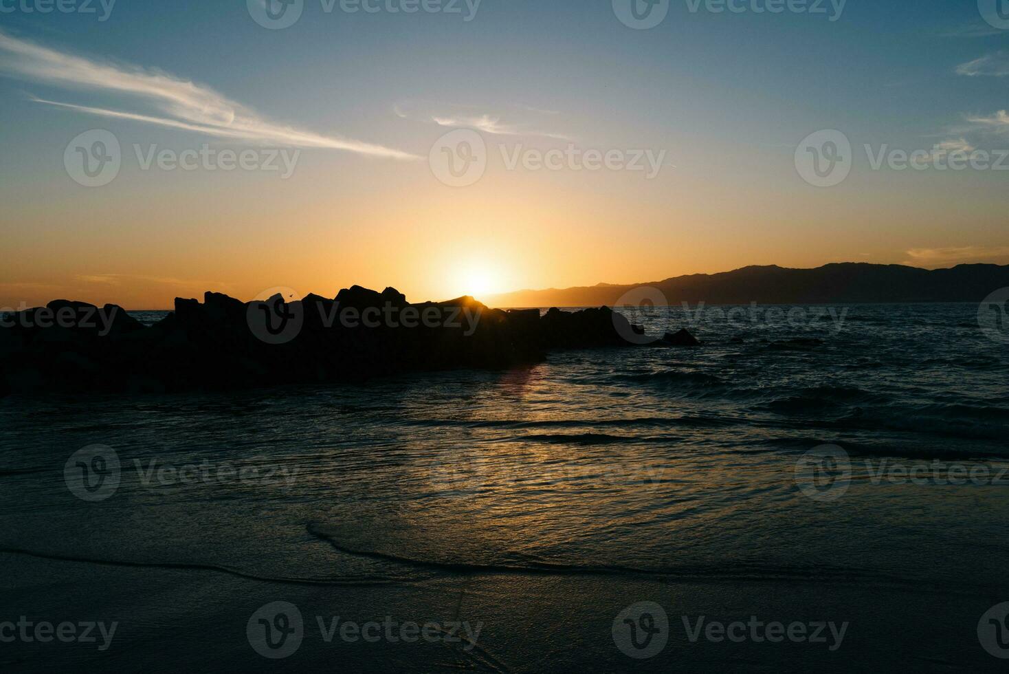 solnedgång Bakom de stenar på de strand foto