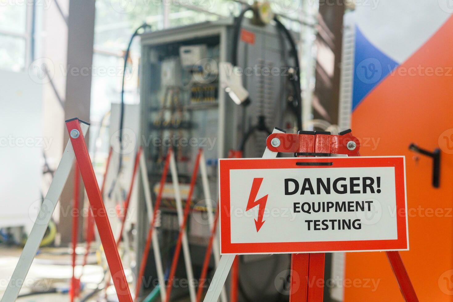 tecken med de inskrift fara Utrustning testning på de staket mot de bakgrund av suddig elektrisk anläggningar i de verkstad foto