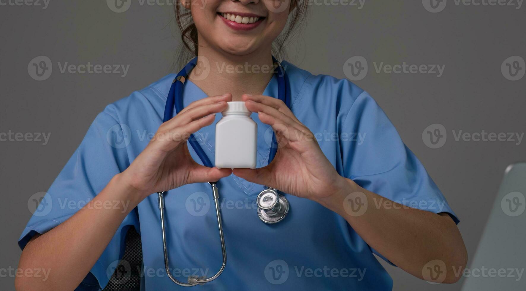 stänga upp, ung asiatisk läkare i en vit medicinsk enhetlig med en stetoskop använder sig av en labb dator och läsplatta till organisera och klassificera mediciner i förberedelse för administrering till patienter. foto