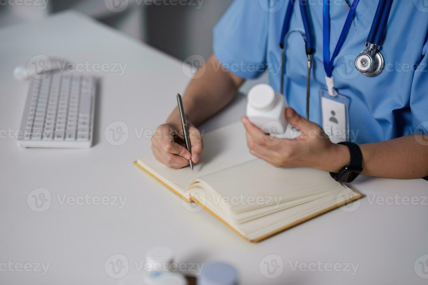 asiatisk kvinna läkare läkare gp terapeut innehav piller flaska i hand skrivning medicinsk recept Sammanträde på arbete skrivbord förskrivning apotek medicin begrepp. närbild se foto