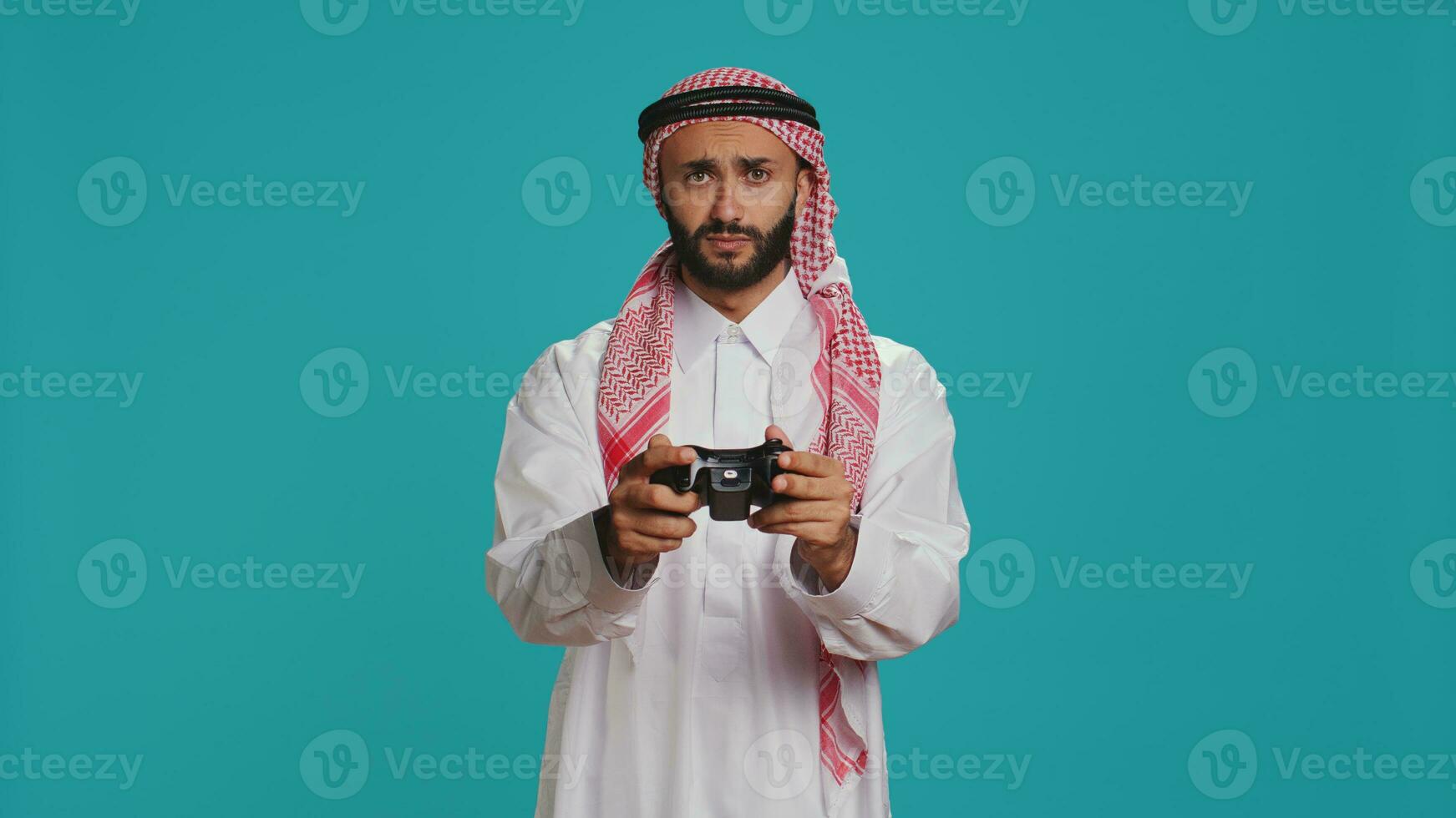 glad vuxen spelar Videospel med joystick, har roligt med uppkopplad gaming tävling över studio bakgrund. muslim gamer i religiös arabicum Kläder tävlar i turnering. foto