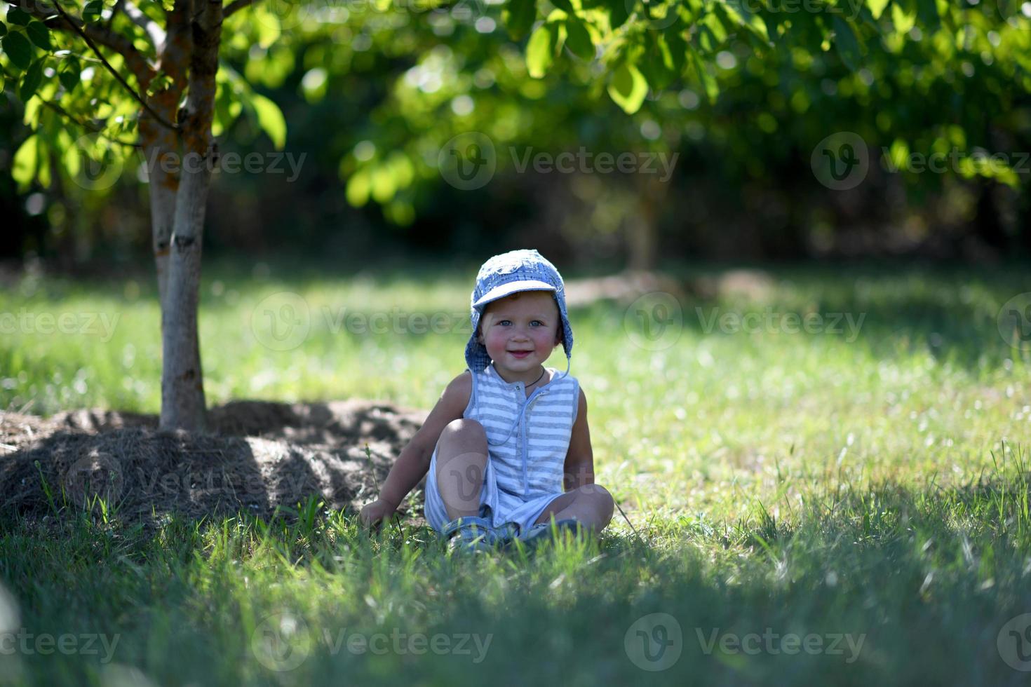 vacker baby pojke i barn trädgård poserar fotograf foto