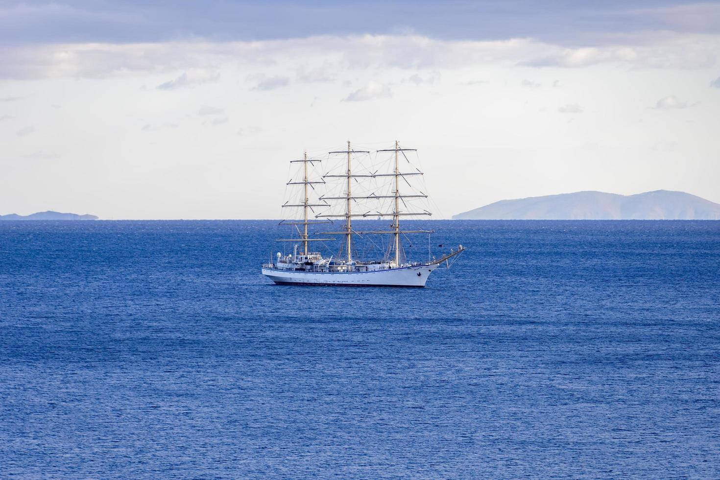 havslandskap med en vit segelbåt vid horisonten foto