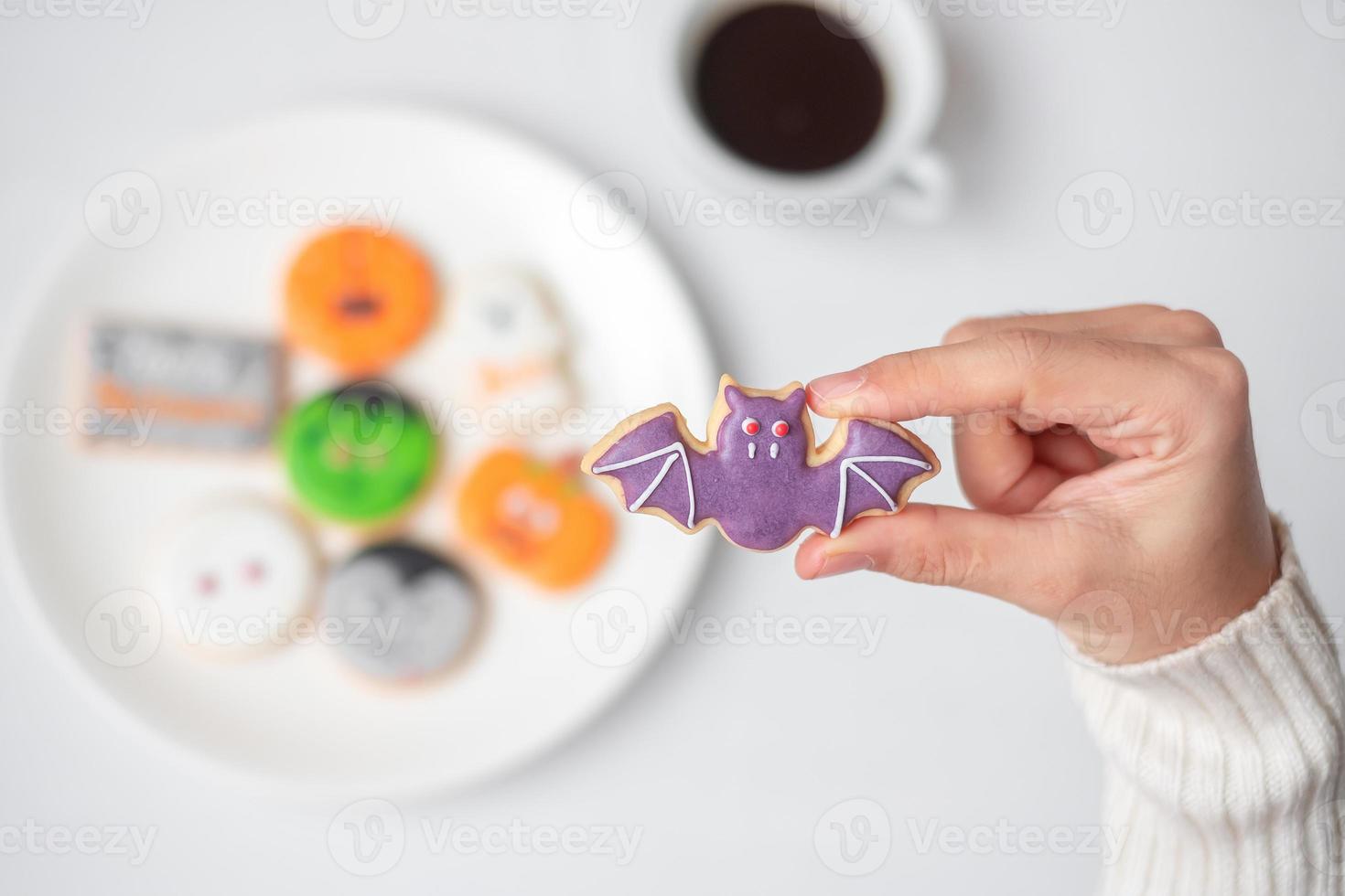 kvinna som håller rolig halloweenkaka under att dricka kaffe. glad halloween dag, trick eller hot, hej oktober, höst höst, traditionell, fest och semester koncept foto