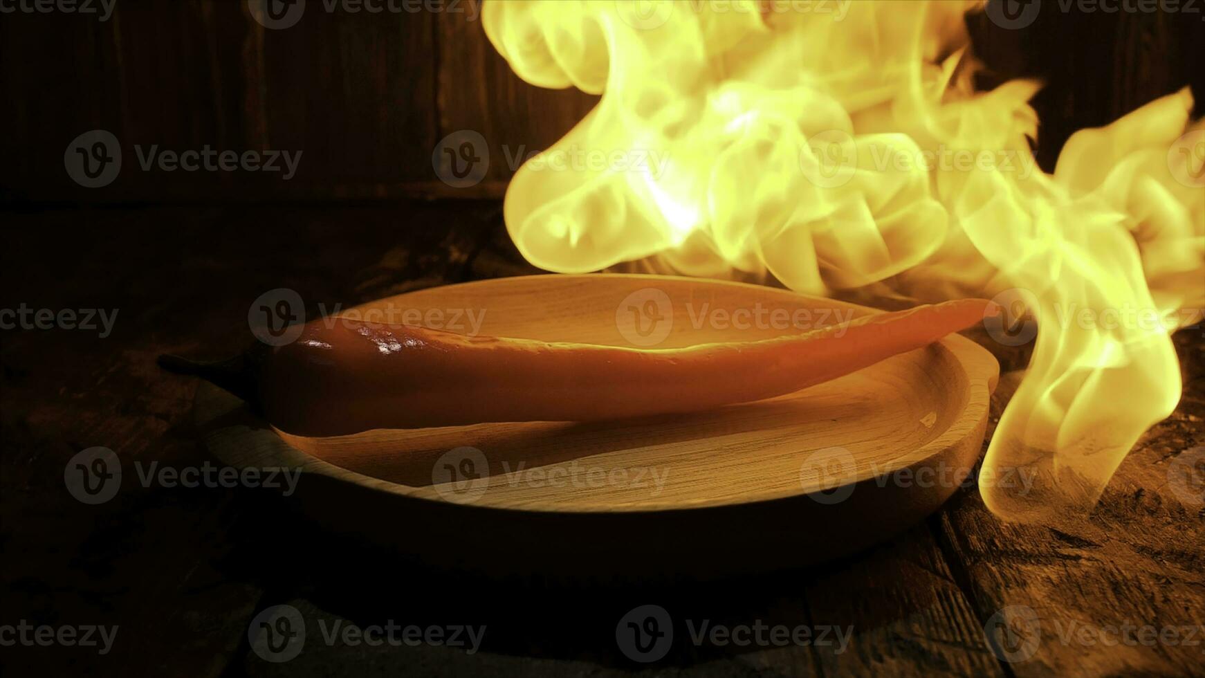 röd varm chili peppar på svart bakgrund med flamma, kryddad mat begrepp. stock antal fot. stänga upp av en peppar liggande på en trä- styrelse under de varm flamma. foto